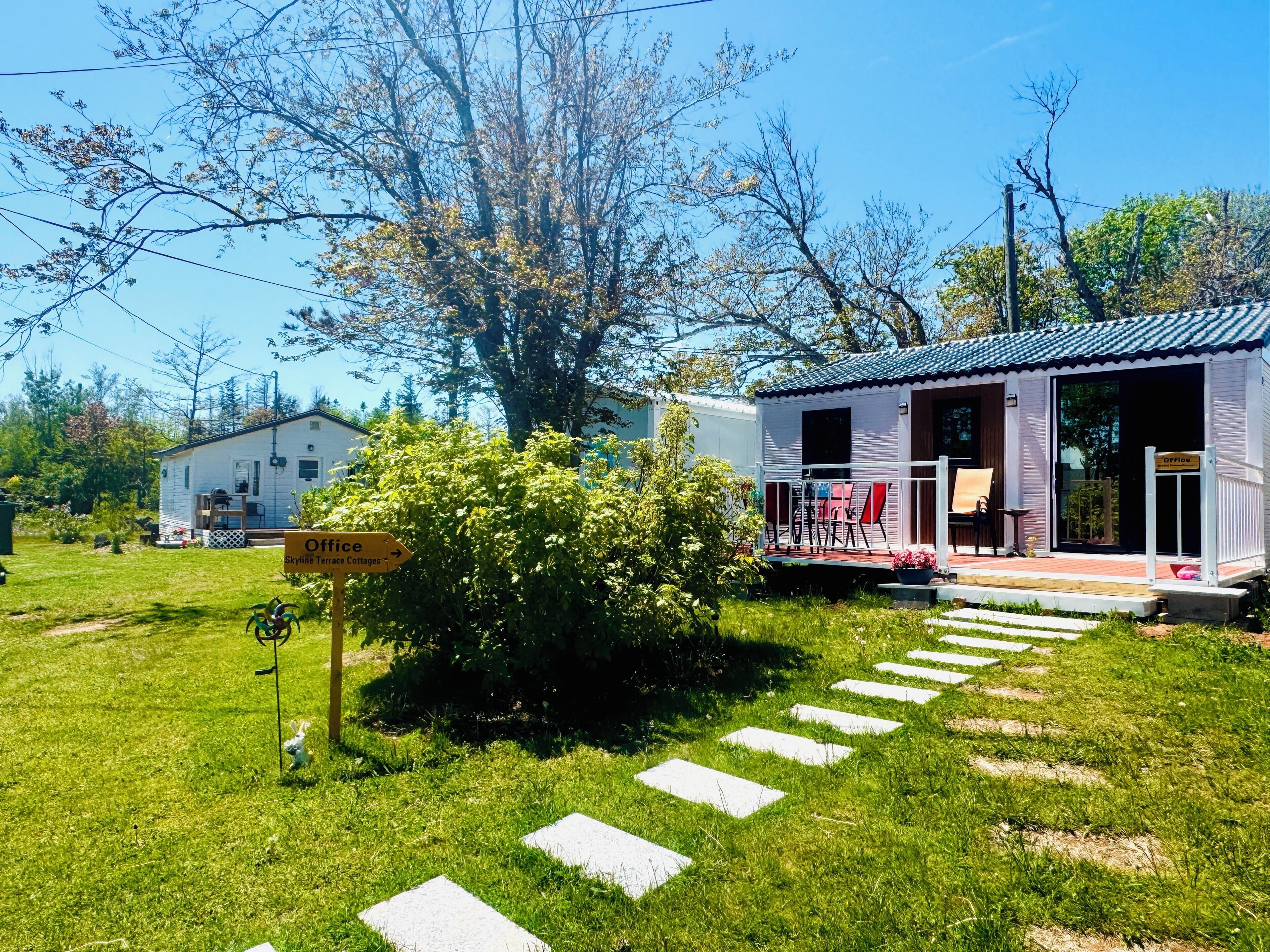 A white building with a porch and a sign indicating an office.