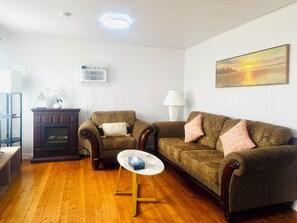A living room with a fireplace, two sofas, a coffee table, and a painting on the wall. - Skyline Terrace Cottages (Stanhope)
