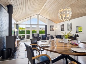 Et moderne spiseområde med et stort træbord, sorte læderstole og en globus-pendel.