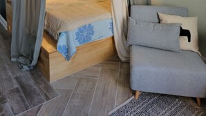 Un lit à baldaquin à quatre poteaux, avec une structure en bois, des rideaux gris et une couvre-lit à motifs floraux bleus.