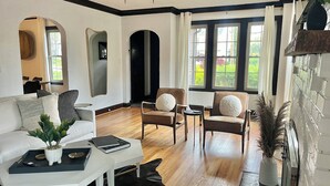 Ein modernes Wohnzimmer mit einem weißen Sofa, zwei Sesseln, einem Couchtisch und einem Kamin.