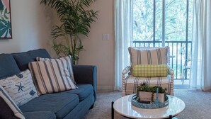 A living room with a blue sofa, striped armchair, and a round coffee table with a decorative tray. - Davenport Andros Condo Retreat (Davenport)