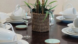 A dining table set with white dishes, a woven basket with a plant, and a framed picture on the wall. - Davenport Andros Condo Retreat (Davenport)