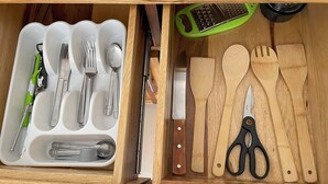 Un tiroir contenant des ustensiles et des outils de cuisine, notamment des fourchettes, des cuillères, un couteau et une paire de ciseaux.