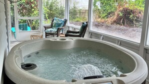 Un jacuzzi con panel de control, rodeado de sillas de mimbre y una terraza de madera.