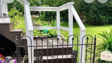 A white wooden staircase with a metal railing leading to a garden area.