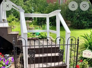 A white wooden staircase with a metal railing leading to a garden area.