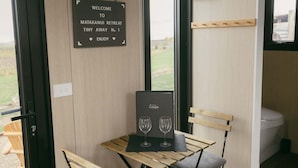 Een knus kamertje met een welkomstbord, een tafel met twee wijnglazen en uitzicht op de omgeving.
