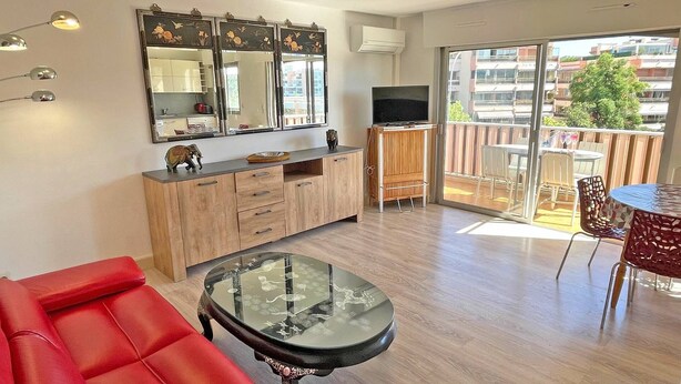Una sala de estar moderna con un sofá rojo, una mesa de centro de vidrio, un aparador de madera y un televisor.