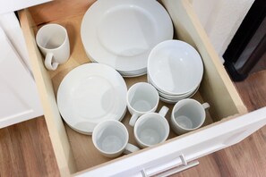 Un cajón con platos, tazones y tazas blancos.