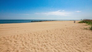 Una extensa playa de arena con cielo azul despejado y mar tranquilo.