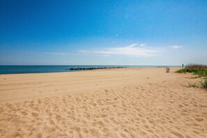 A wide sandy beach with a clear blue sky and calm sea.