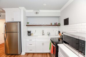Une cuisine moderne avec des meubles blancs, un réfrigérateur en acier inoxydable, un four à micro-ondes et une cuisinière.