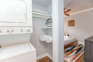 A laundry area with a washing machine, a dryer, and a shelf with folded towels.