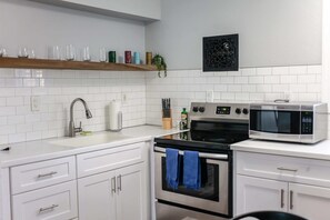 Eine Küche mit weißen Schränken, einem Edelstahlbackofen, einer Mikrowelle und einem Spülbecken mit modernem Wasserhahn.