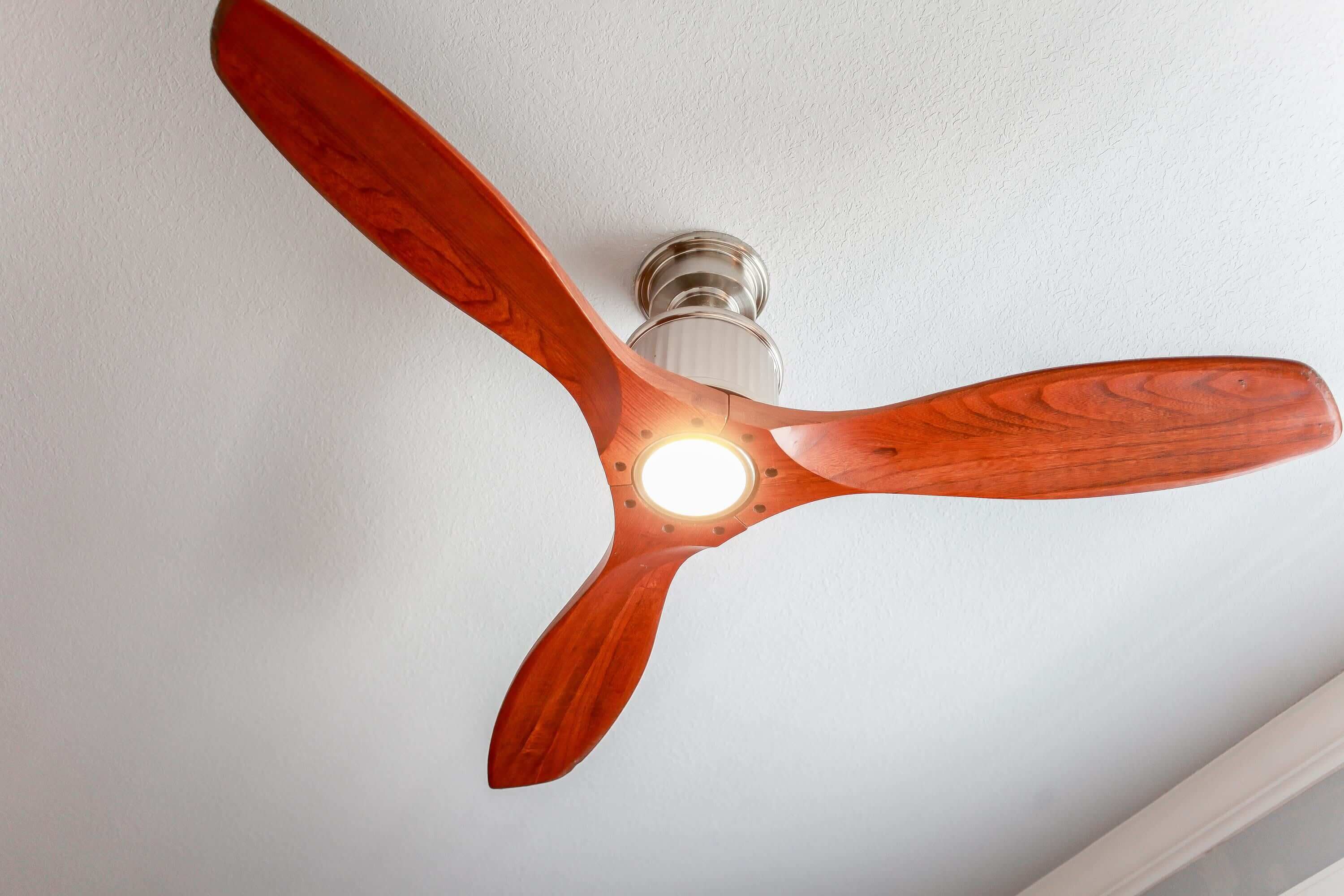 A ceiling fan with wooden blades and a light fixture.