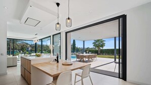 Eine moderne Küche mit einer großen Kochinsel, großen Fenstern und einem Außenbereich mit Pool.