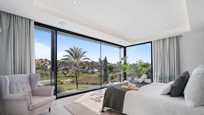 Ein modernes Schlafzimmer mit einem großen Bett, einer Sitzecke und Blick auf einen Golfplatz.