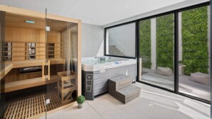 Ein moderner Wellnessraum mit Whirlpool, Holzregalen und einer Glaseinfriedung.