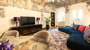 A living room with a television, sofa, and chairs. - MARIA CALLAS LUXURY APPARTAMENT (VERONA)