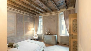 A bedroom with a bed, a dresser, a chair, and a radiator. - MARIA CALLAS LUXURY APPARTAMENT (VERONA)