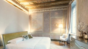A well-lit bedroom with a large bed, a chair, and a dresser. - MARIA CALLAS LUXURY APPARTAMENT (VERONA)