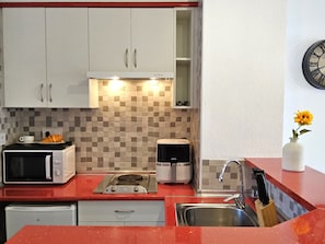 A kitchen with white cabinets, a microwave, a toaster, a coffee maker, and a sink. - Eva Mar by Interhome (Benidorm)
