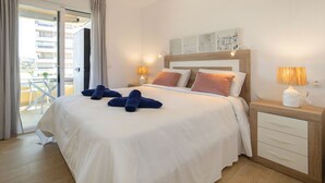 A hotel room with a bed, two bedside lamps, a wooden nightstand, and a view of the balcony. - Turmalina by Interhome (Calpe/Calp)