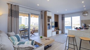 A modern living room with a sofa, a dining table, and a kitchen area with a TV. - Turmalina by Interhome (Calpe/Calp)