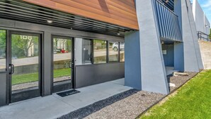 Un edificio moderno con amplias puertas de cristal, techo de listones de madera y fachada de hormigón.