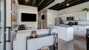 Una cocina moderna con armarios blancos, una isla central y un microondas empotrado.