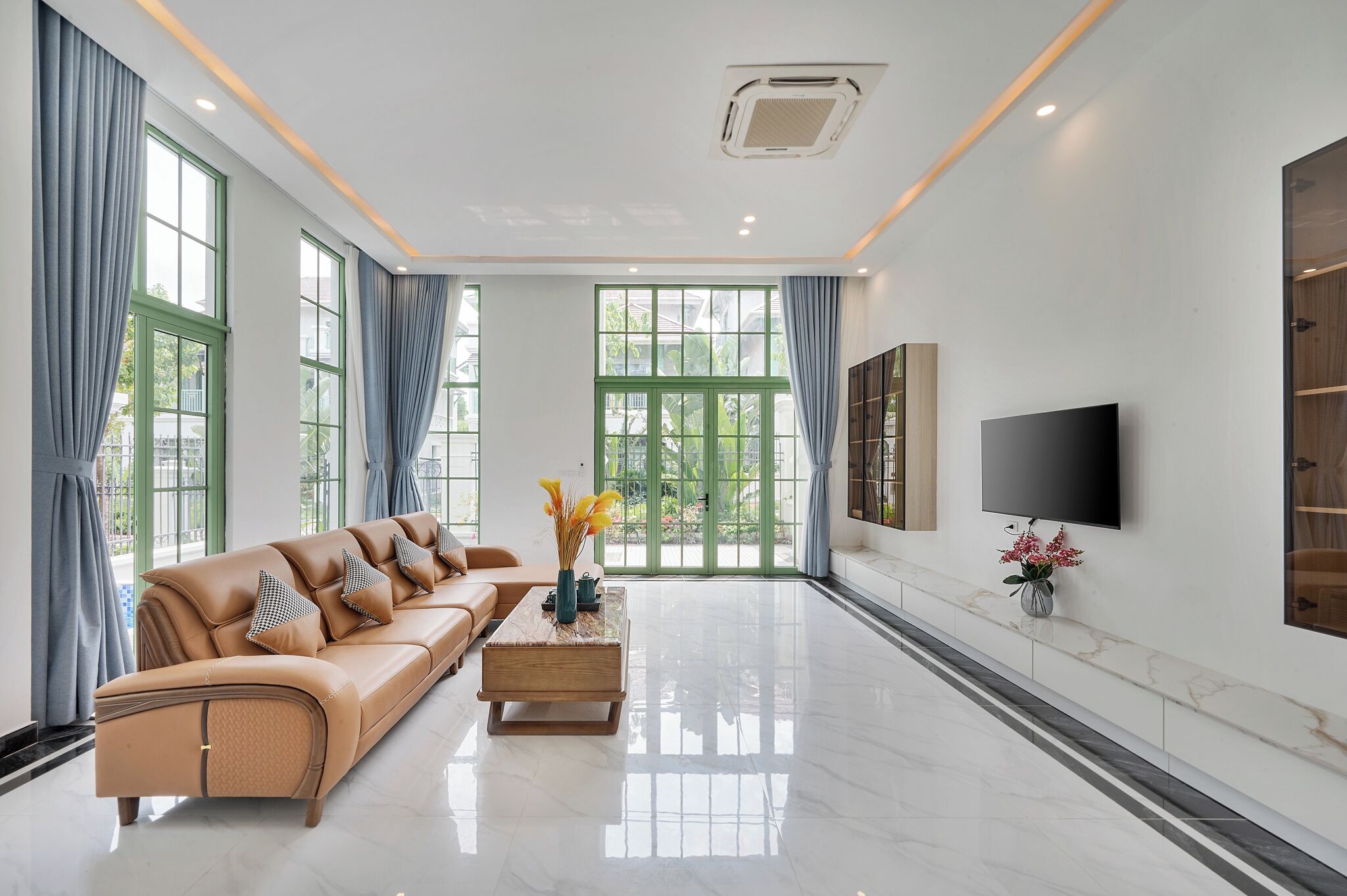 A modern living room with a leather sofa, a wooden coffee table, and a flat-screen TV mounted on the wall.