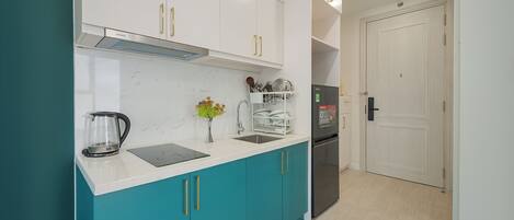 A modern kitchen with teal cabinets, a stainless steel refrigerator, and a white countertop.