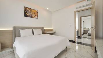 Una habitación de hotel moderna con una cama grande, una mesita de noche, un aire acondicionado y un cuadro en la pared.