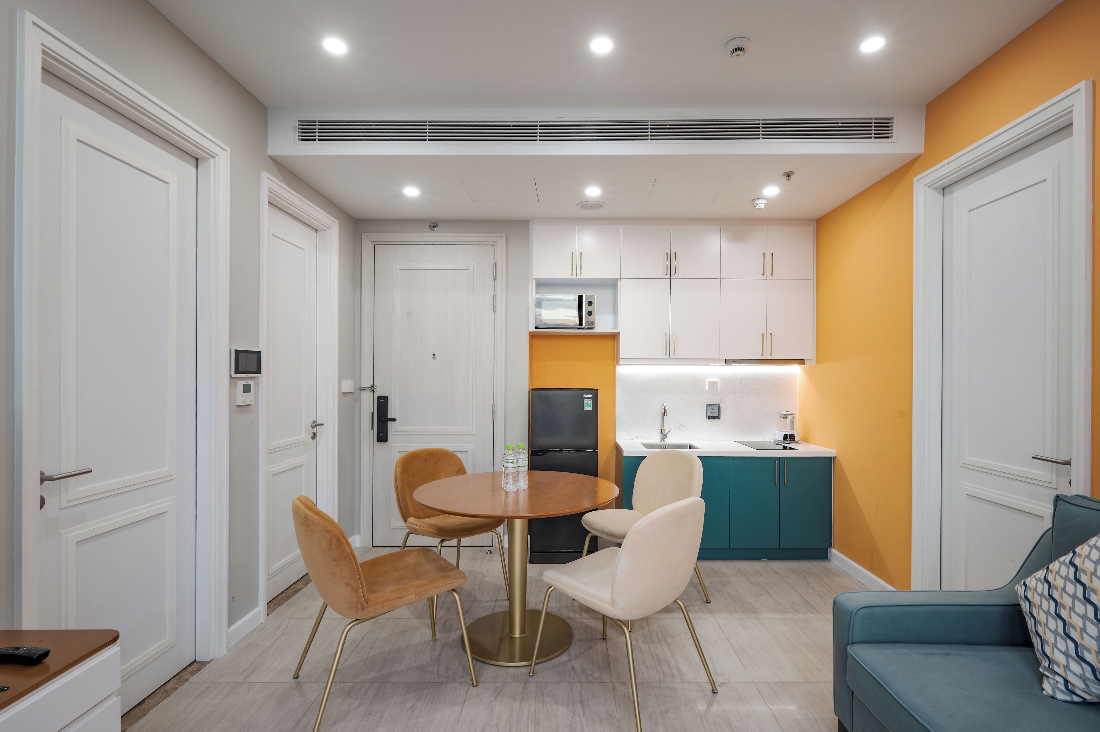 A modern kitchen with white cabinets, a black refrigerator, and a teal countertop.