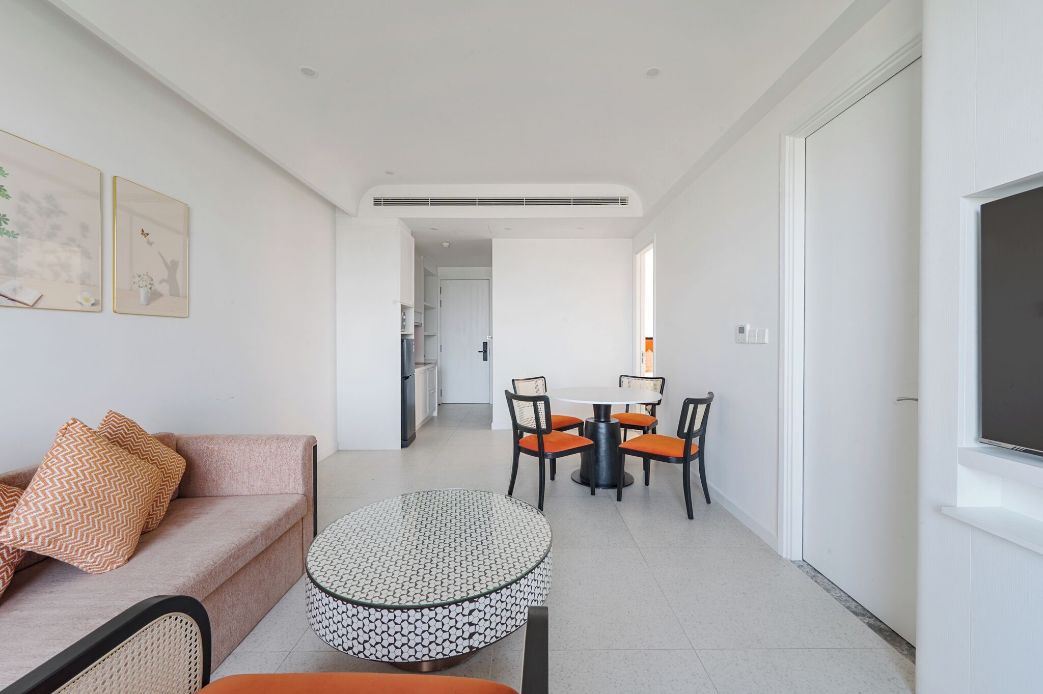 Una sala de estar moderna con un sofá, una mesa redonda de centro y un comedor con una mesa y sillas.