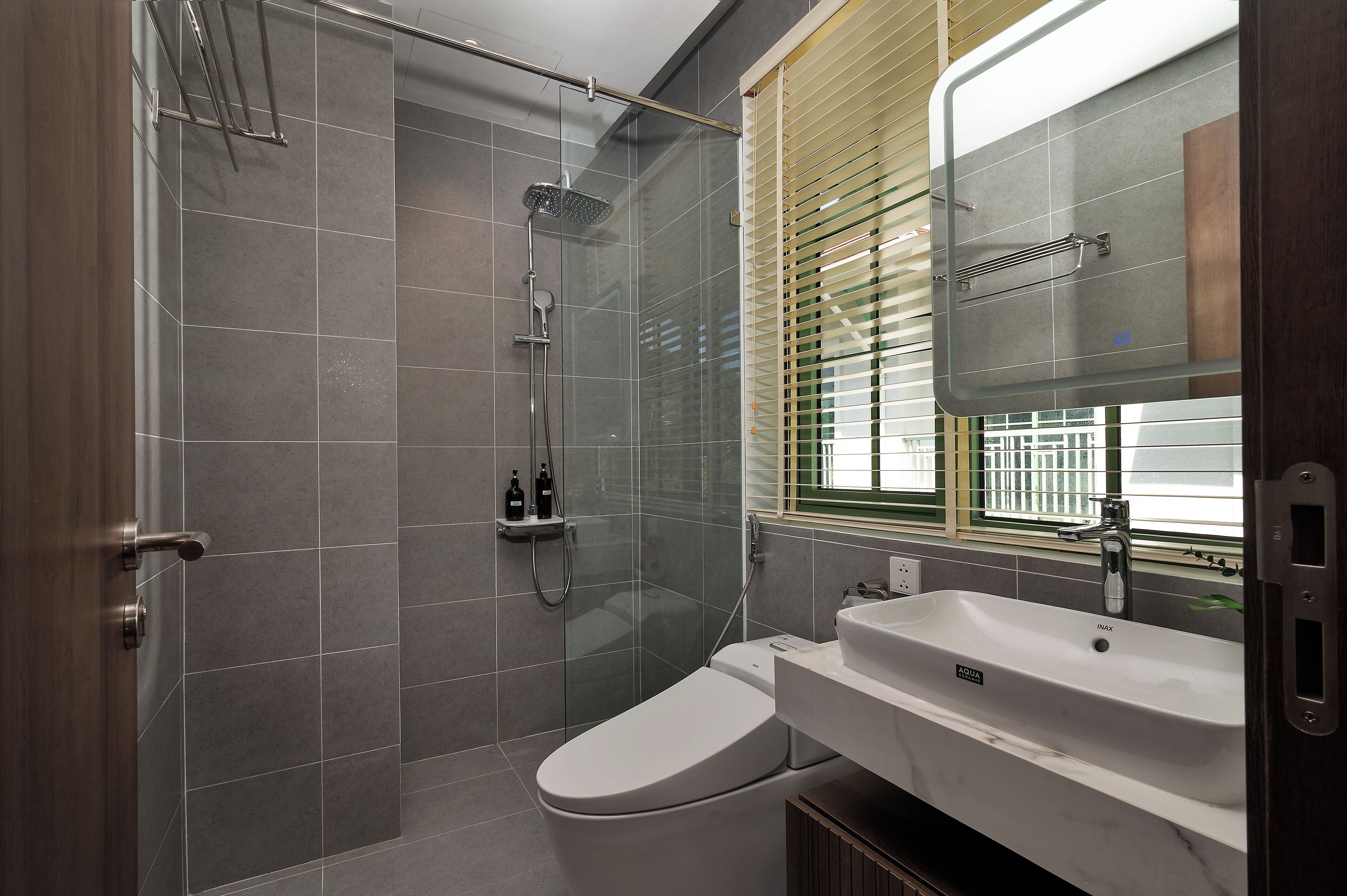 A modern bathroom with a shower, toilet, and sink.