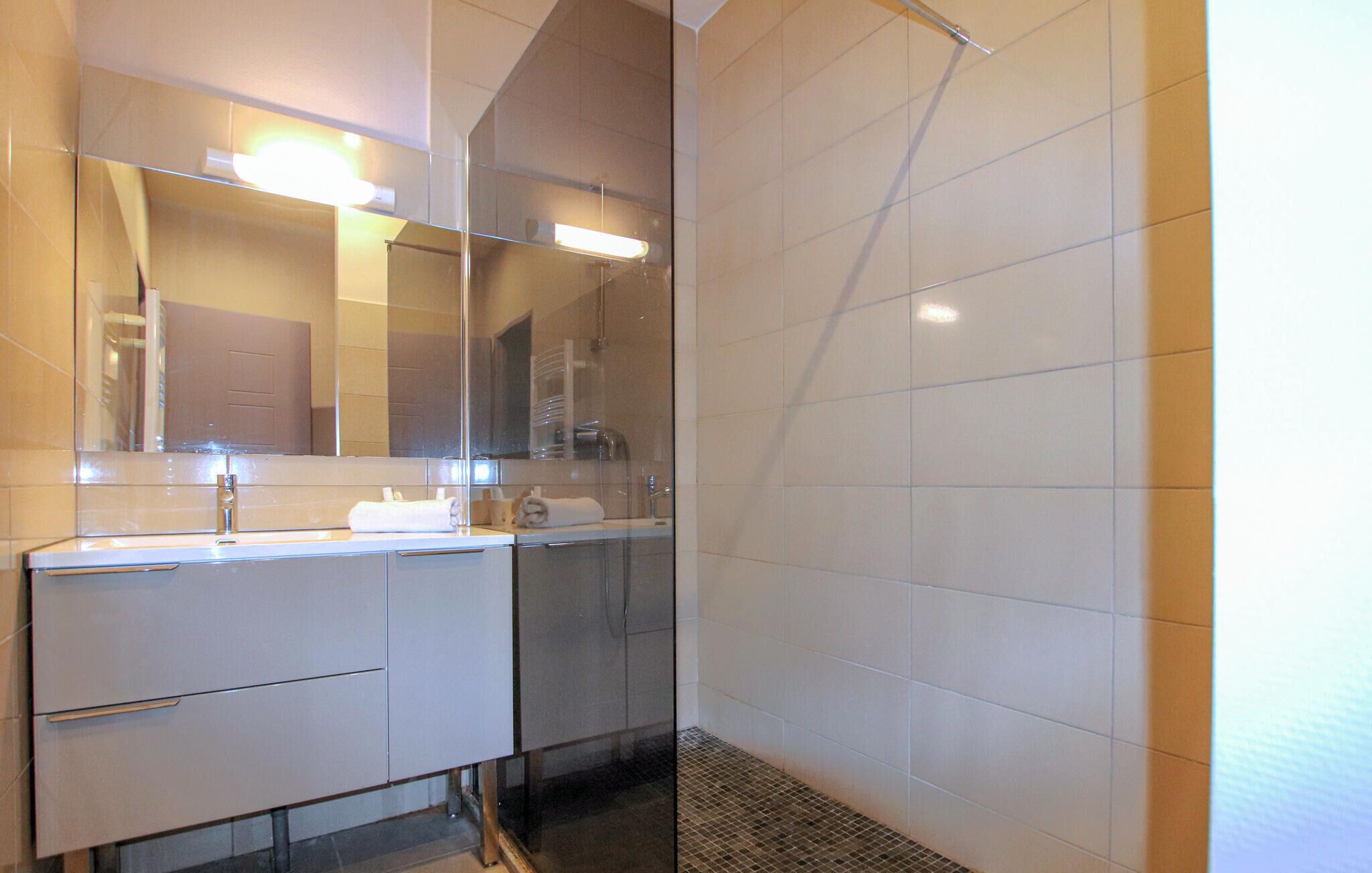 Une salle de bain moderne dotée d’une douche à parois de verre, d’un grand miroir et d’un meuble-lavabo à deux vasques.