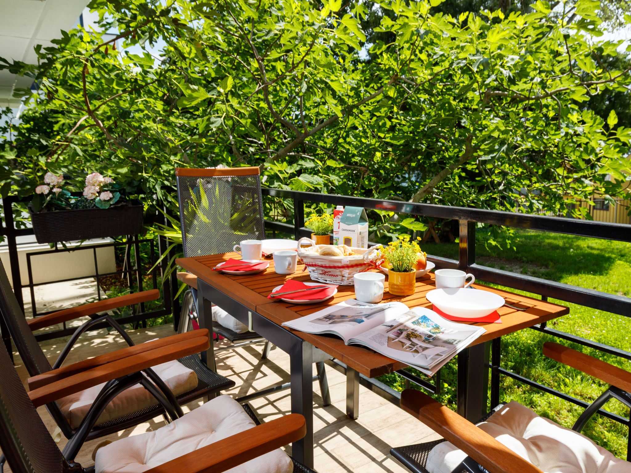 Un espace de restauration en plein air avec une table dressée pour deux personnes, entourée de chaises, et offrant une vue sur une végétation luxuriante.