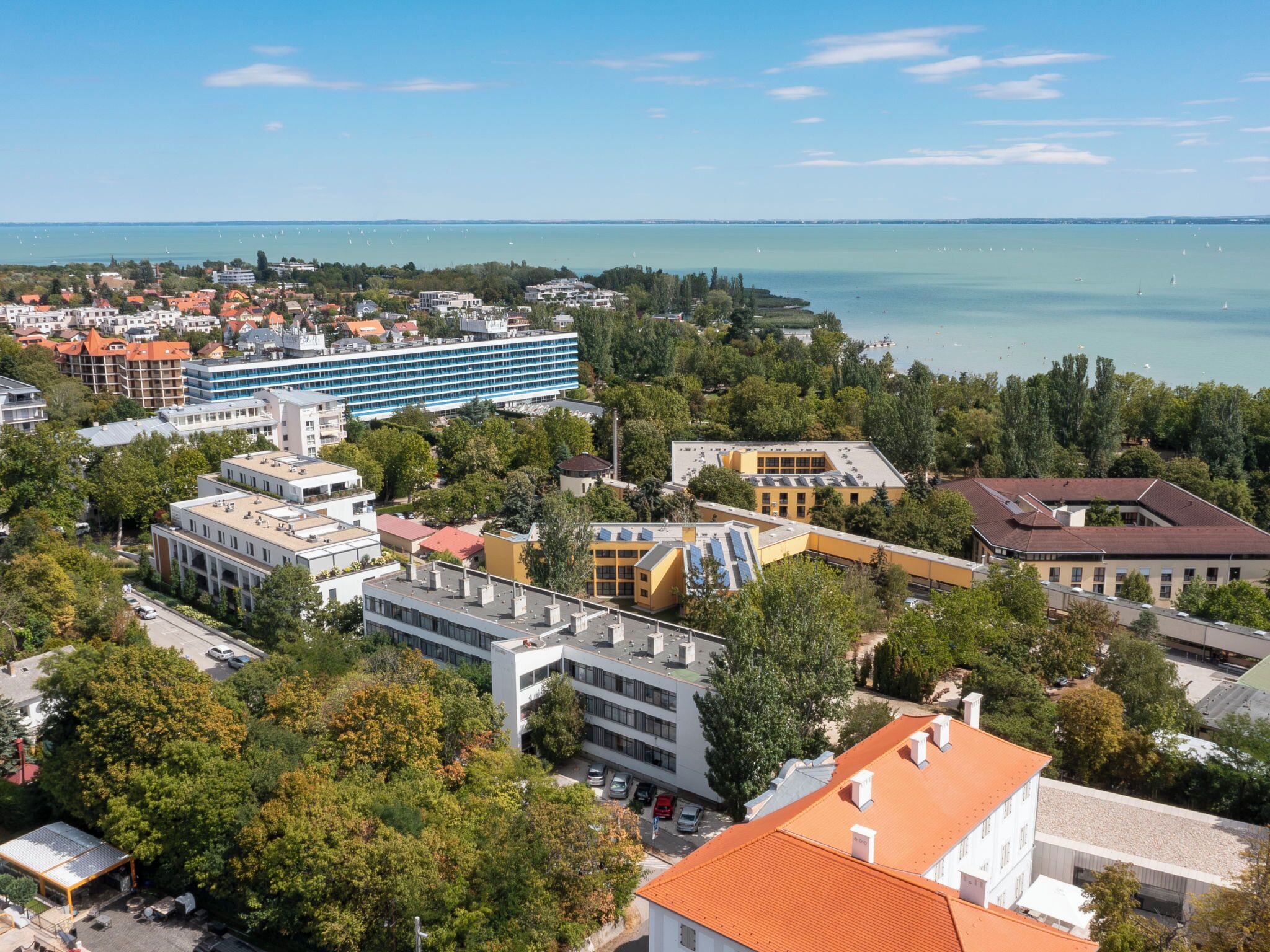 A coastal town with a mix of modern and traditional buildings, a marina with boats, and a clear view of the sea.