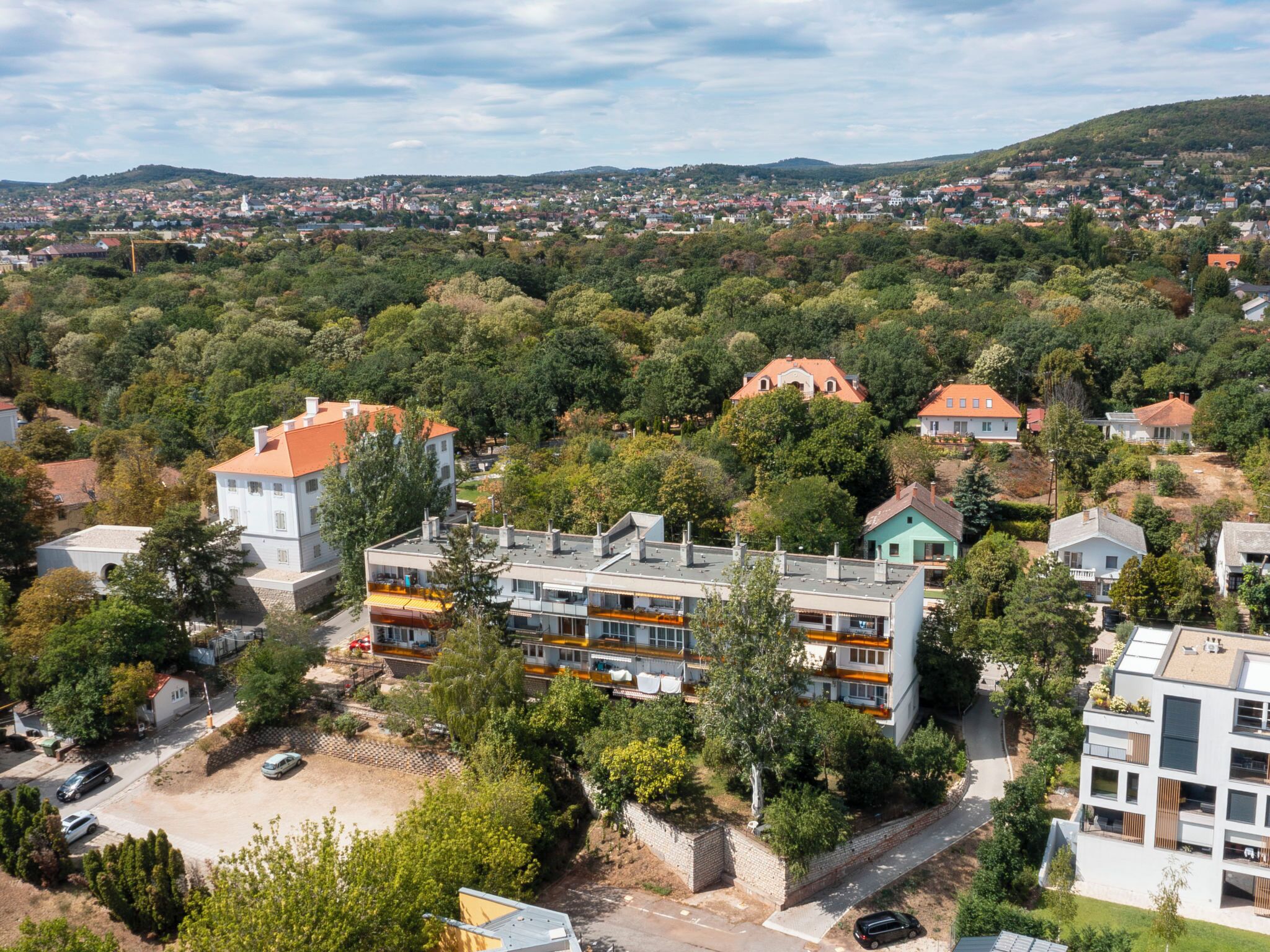 Ein Wohngebiet mit mehrstöckigen Gebäuden, einer Straße und umgebender Bepflanzung.
