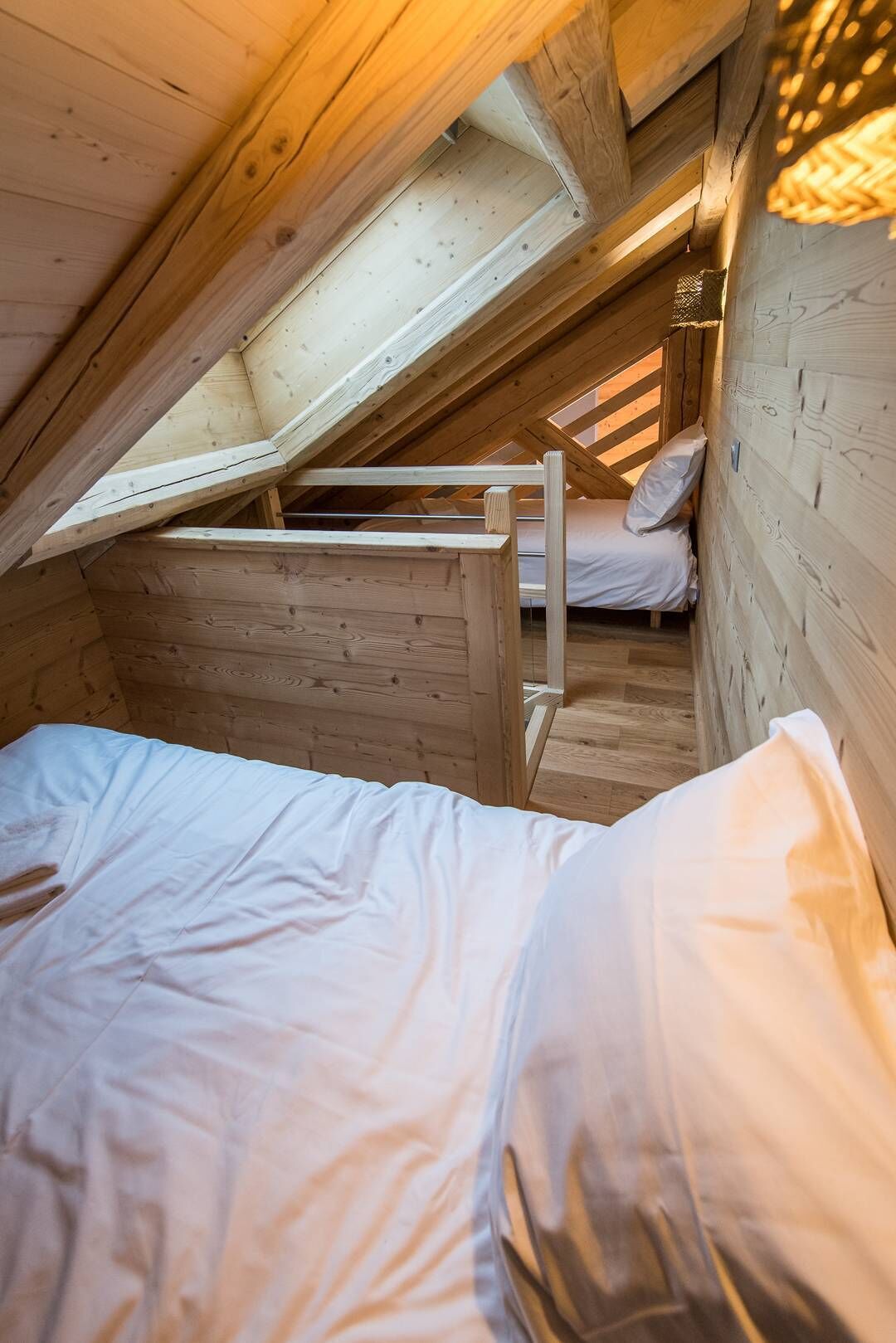 Un pequeño dormitorio abuhardinado de madera con una cama litera y una cama individual.