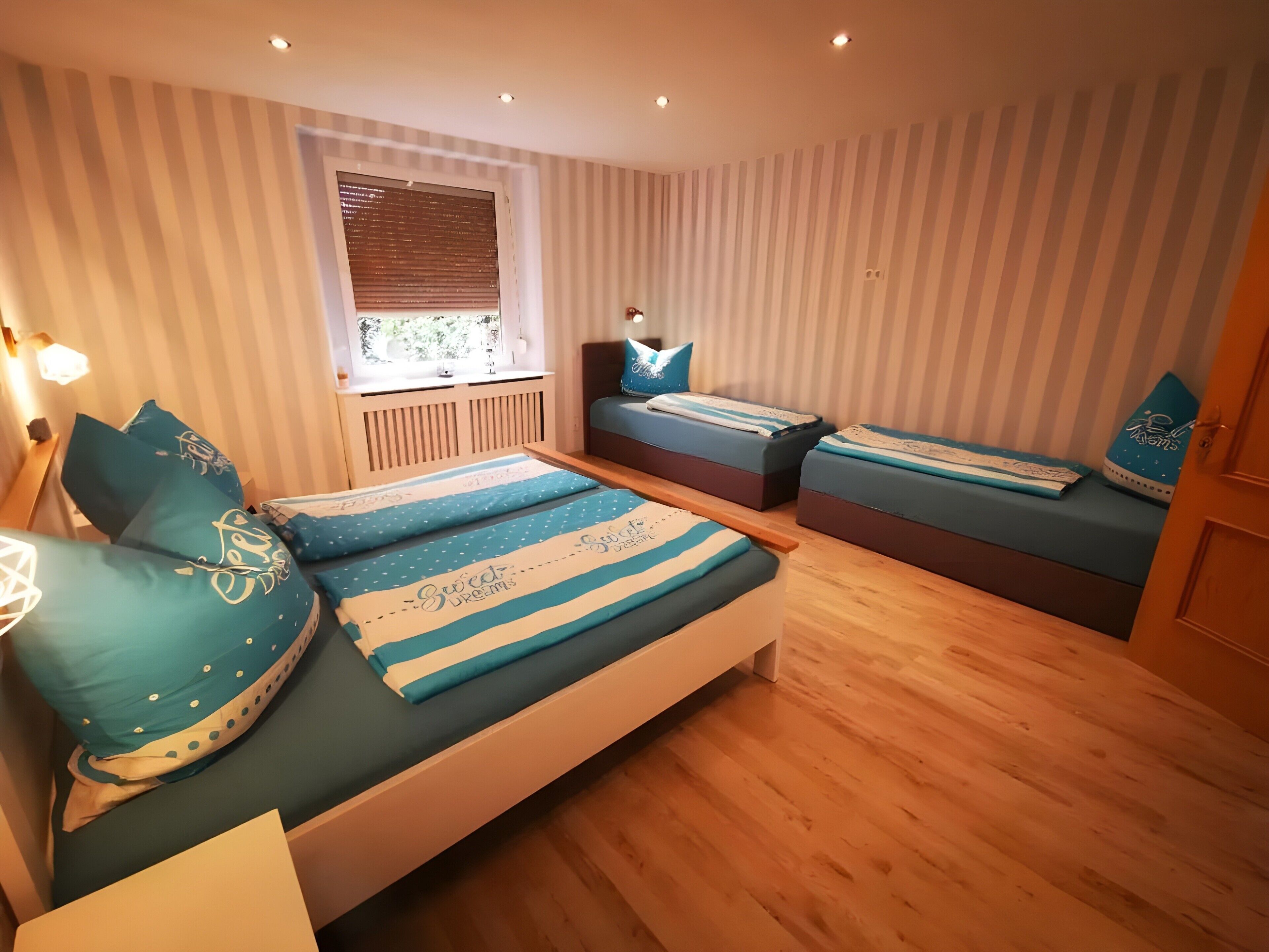 Ein Schlafzimmer mit einem Bett, zwei Nachttischen, einem Fenster mit Jalousien und einer Tür.