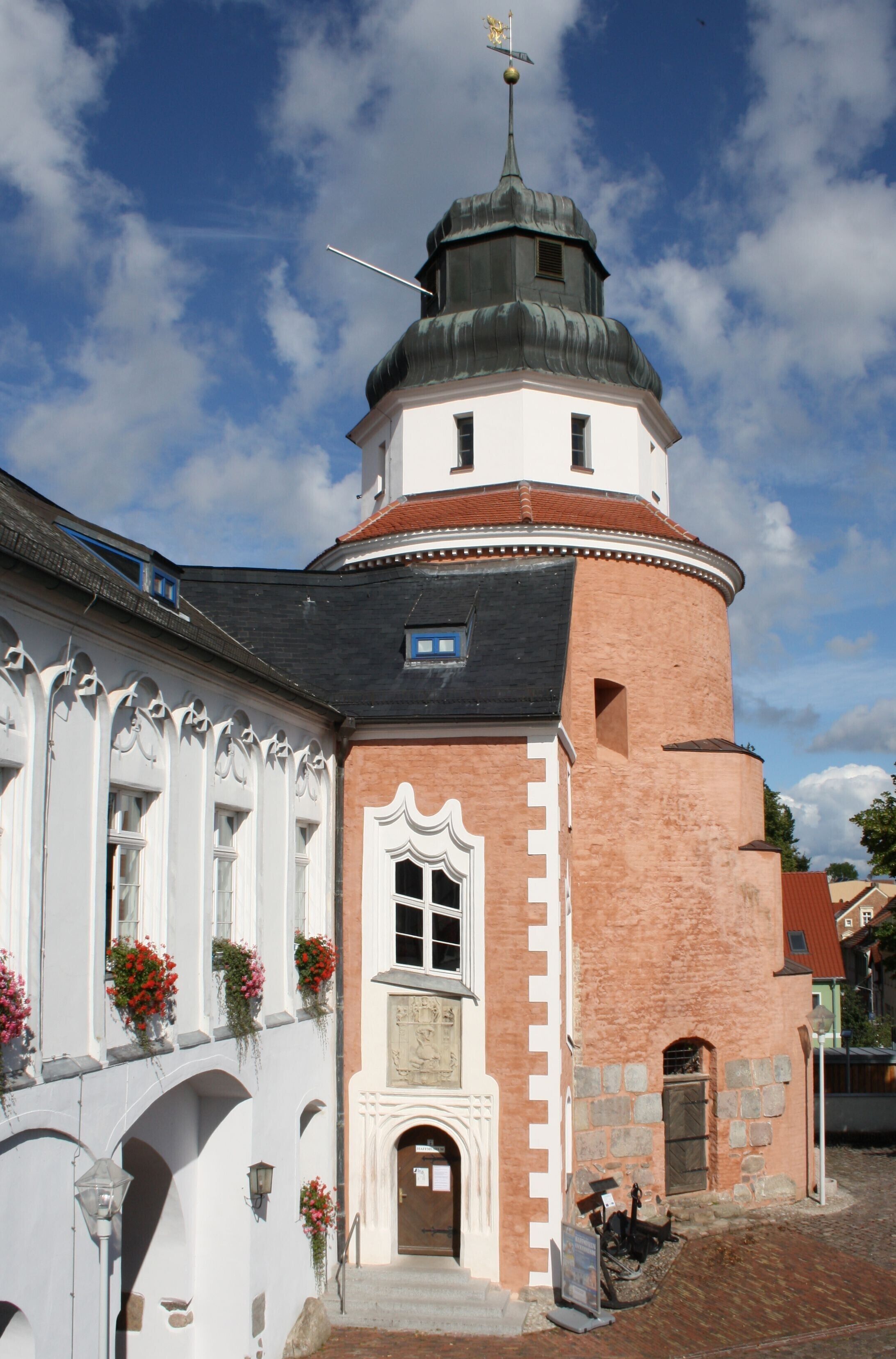 Een historisch gebouw met een toren, gebogen ramen en een gevel van baksteen.