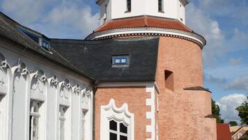 Een historisch gebouw met een toren, gebogen ramen en een gevel van baksteen.
