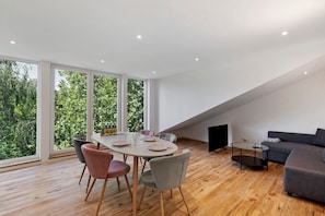 A modern interior with a dining table, chairs, a sofa, and a TV.