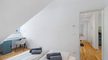 Quarto com escrivaninha, duas camas e vista para um corredor.