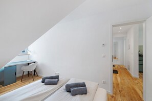 Une chambre avec un bureau, deux lits et une vue sur un couloir.