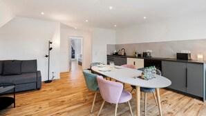 Una cocina moderna con comedor, piso de madera y sofá gris.