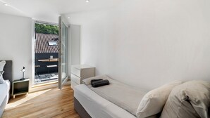 Un dormitorio moderno con cama, mesita de noche y vistas al exterior a través de una puerta de cristal.